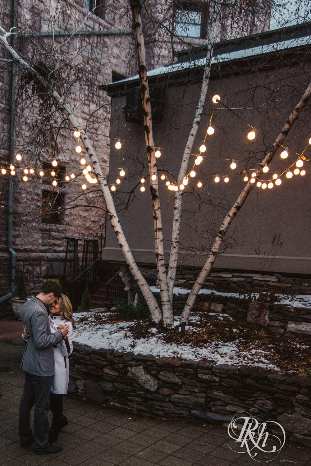 Man and woman in winter coats dance in front of the Van Dusen Mansion in Minneapolis, Minnesota.
