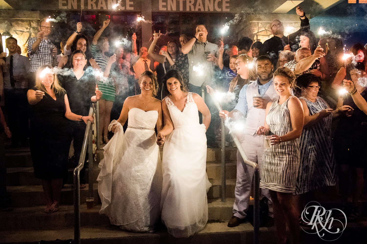 Lesbian brides and guests dance hold sparklers at night at Spirit Mountain in Duluth, Minnesota.