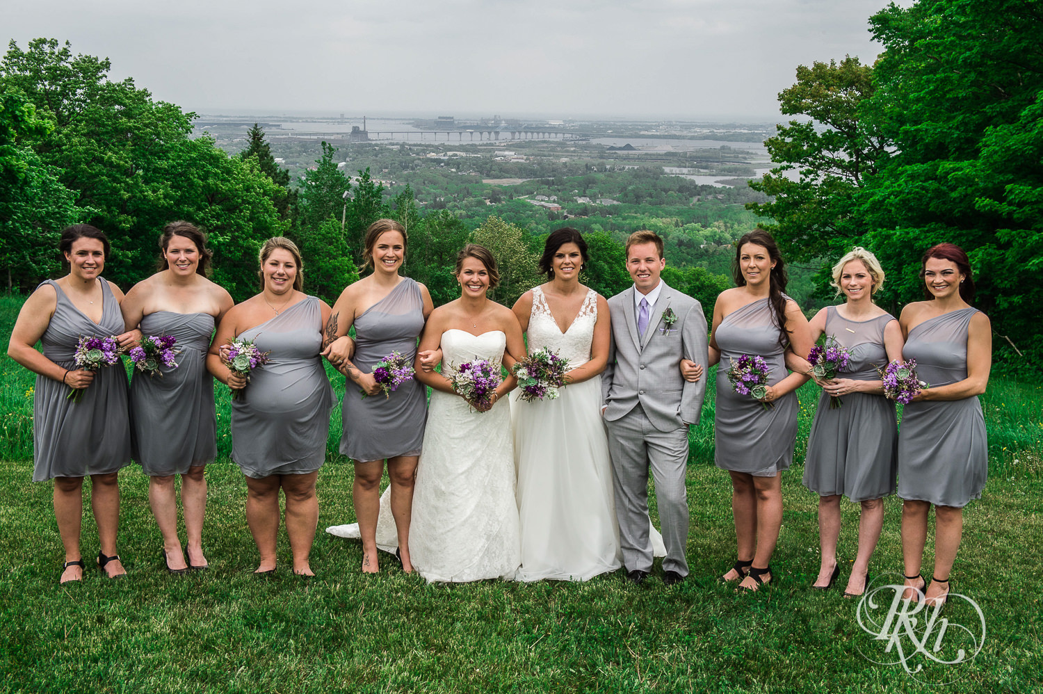Lesbian brides smile with wedding party outside at Spirit Mountain in Duluth, Minnesota.