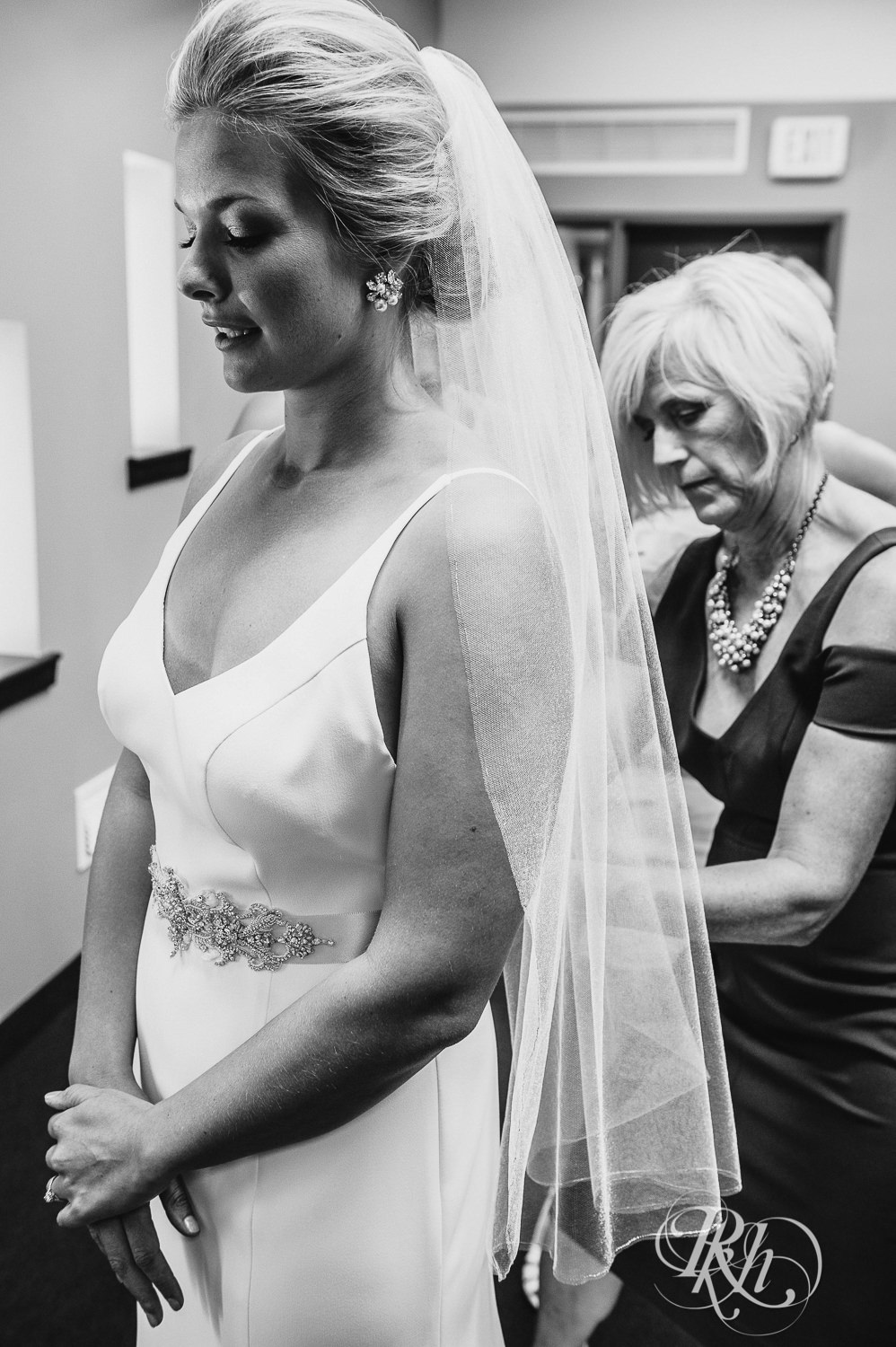 Mom helps a bride get into her dress on her wedding day.
