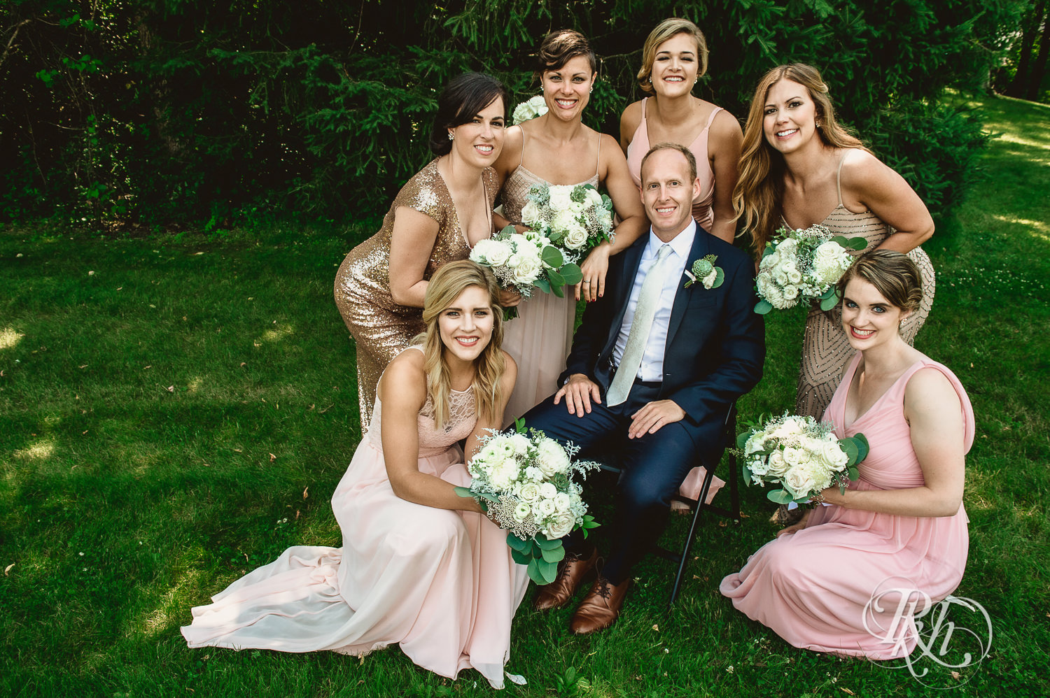 Groom laughs with bridesmaids on his wedding day in the woods in Minneapolis, Minnesota.