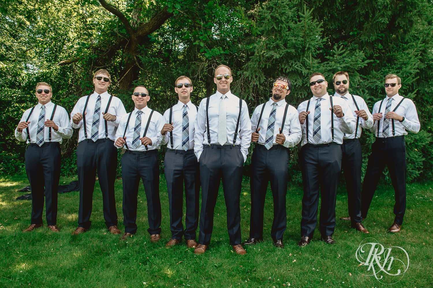 Groom laughs with groomsmen on his wedding day in the woods in Minneapolis, Minnesota.