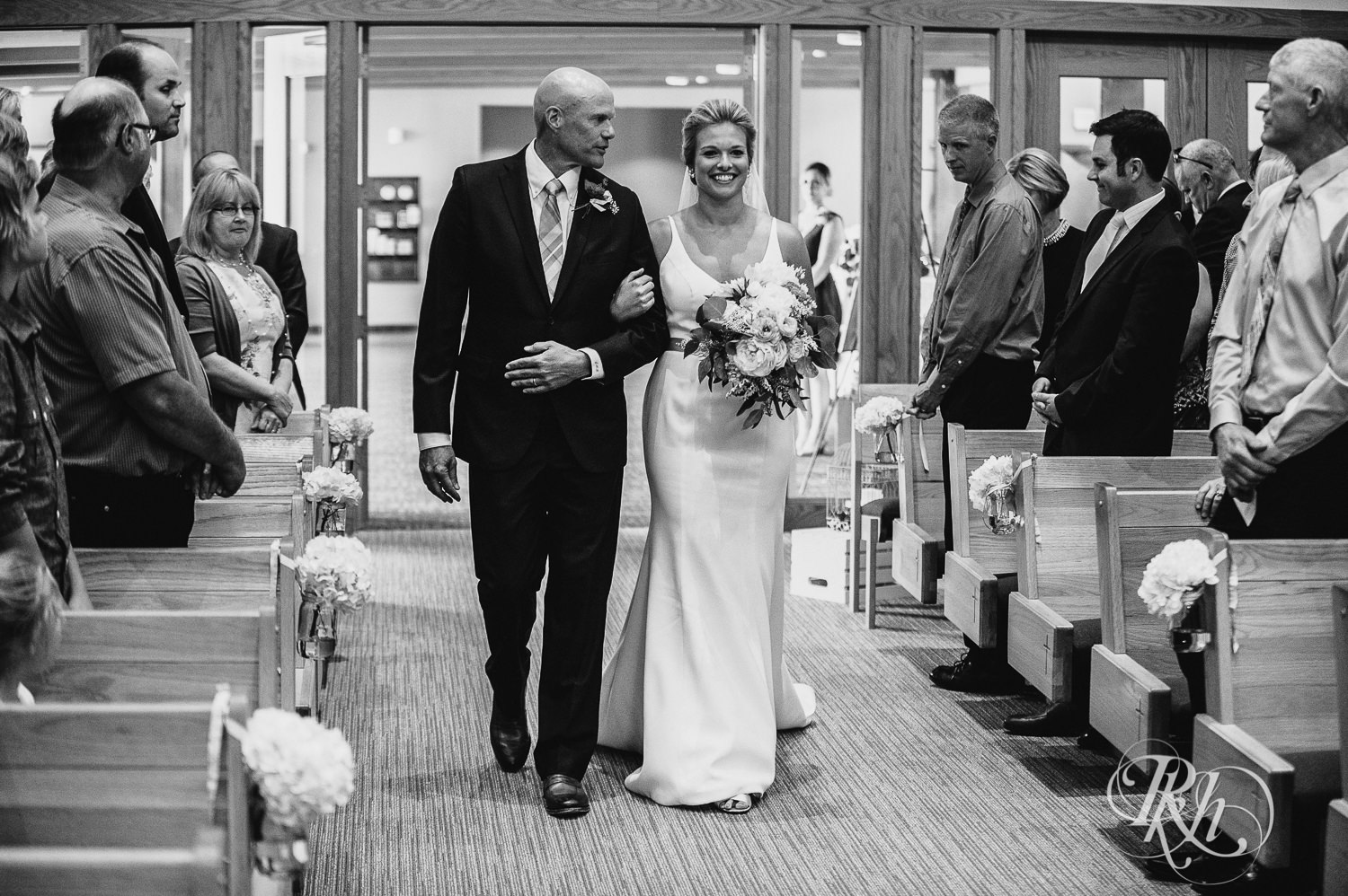 Bride and her dad walk down the aisle during a church wedding ceremony in Minneapolis, Minnesota.