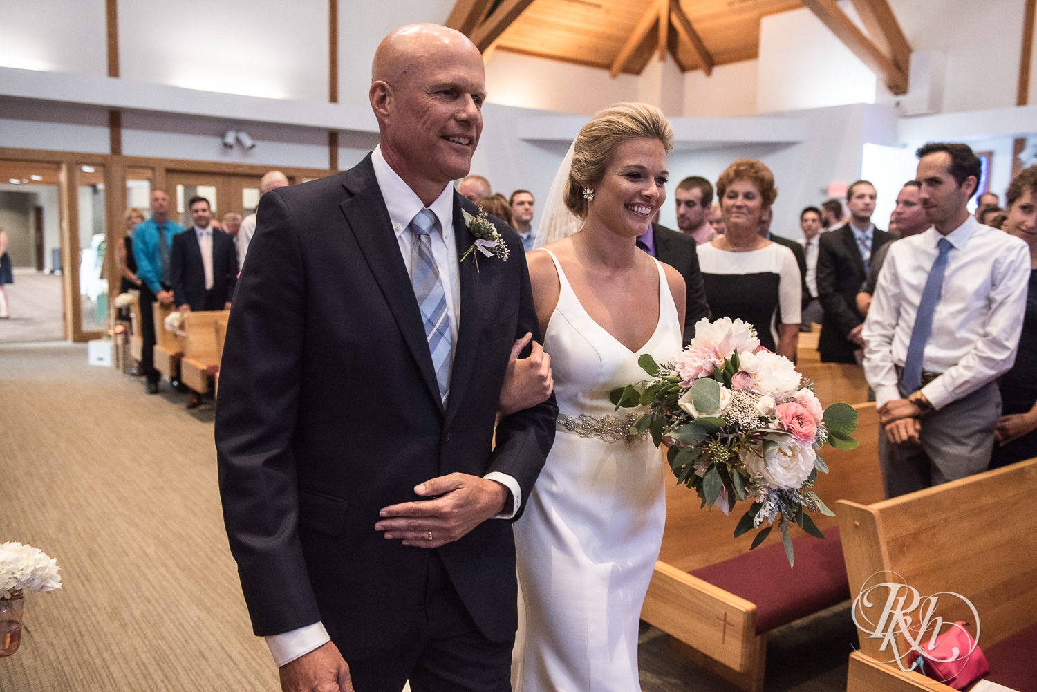 Bride and her dad walk down the aisle during a church wedding ceremony in Minneapolis, Minnesota.