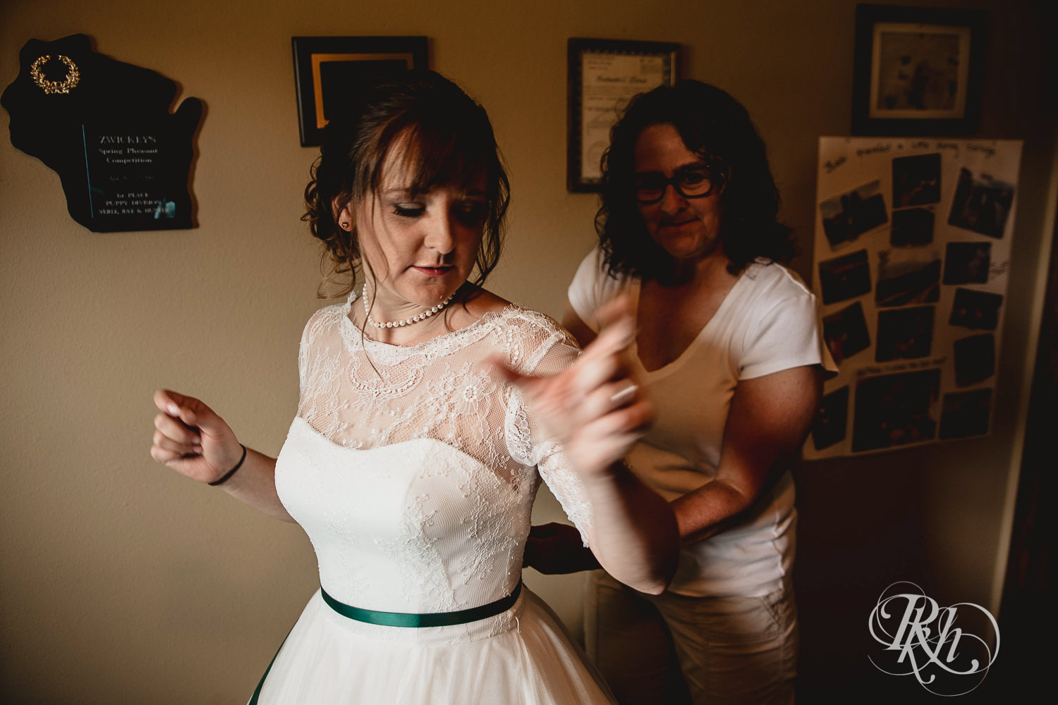 Mom helps bride into wedding dress before wedding in Elk Mound, Wisconsin.