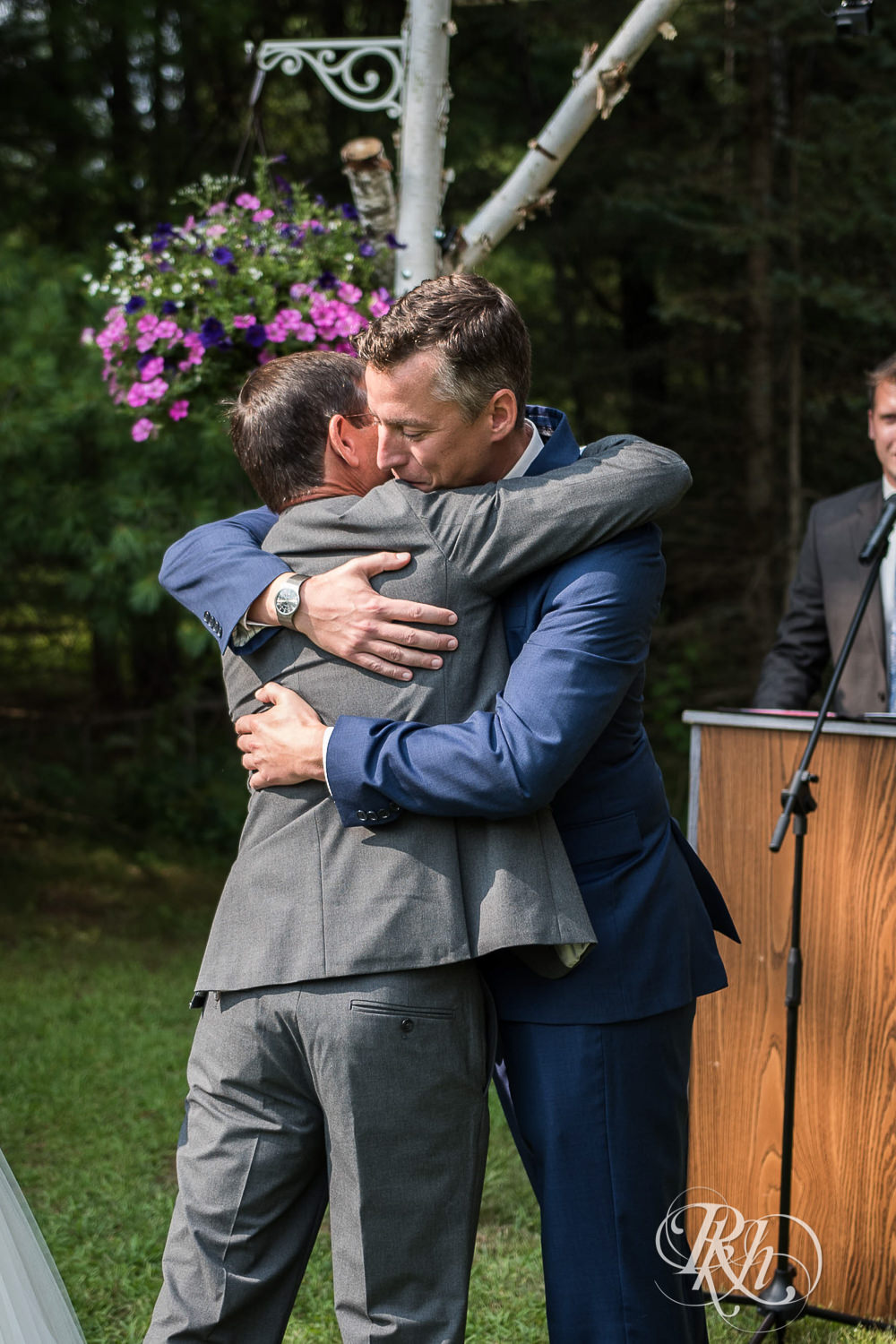 Dad hugs groom during outdoor wedding ceremony in Elk Mound, Wisconsin.