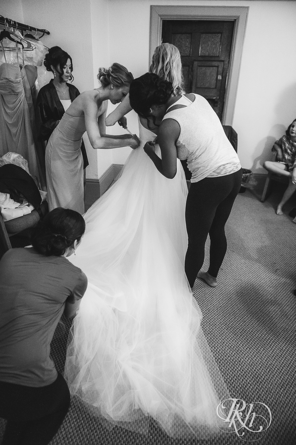 Wedding party helps bride get dressed on her wedding day before the ceremony.