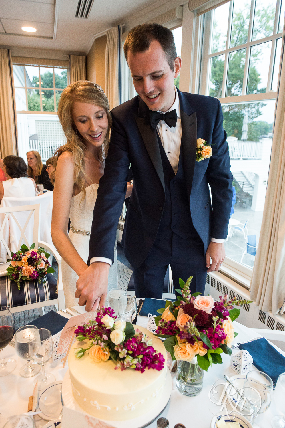 Bride and groom cut cake during reception at White Bear Yacht Club in Dellwood, Minnesota.