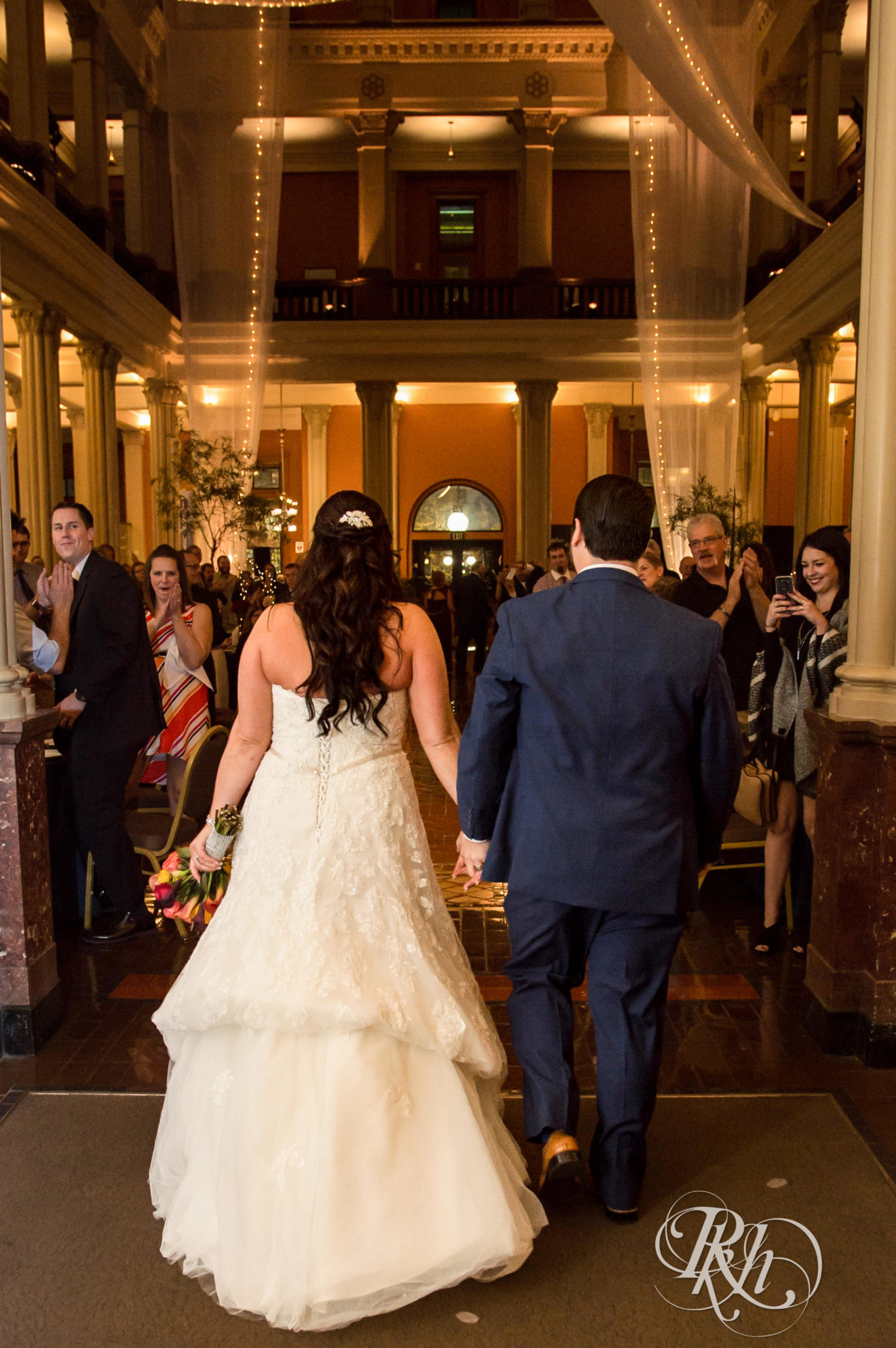 Bride and groom enter wedding reception on wedding day at Landmark Center in Saint Paul, Minnesota.