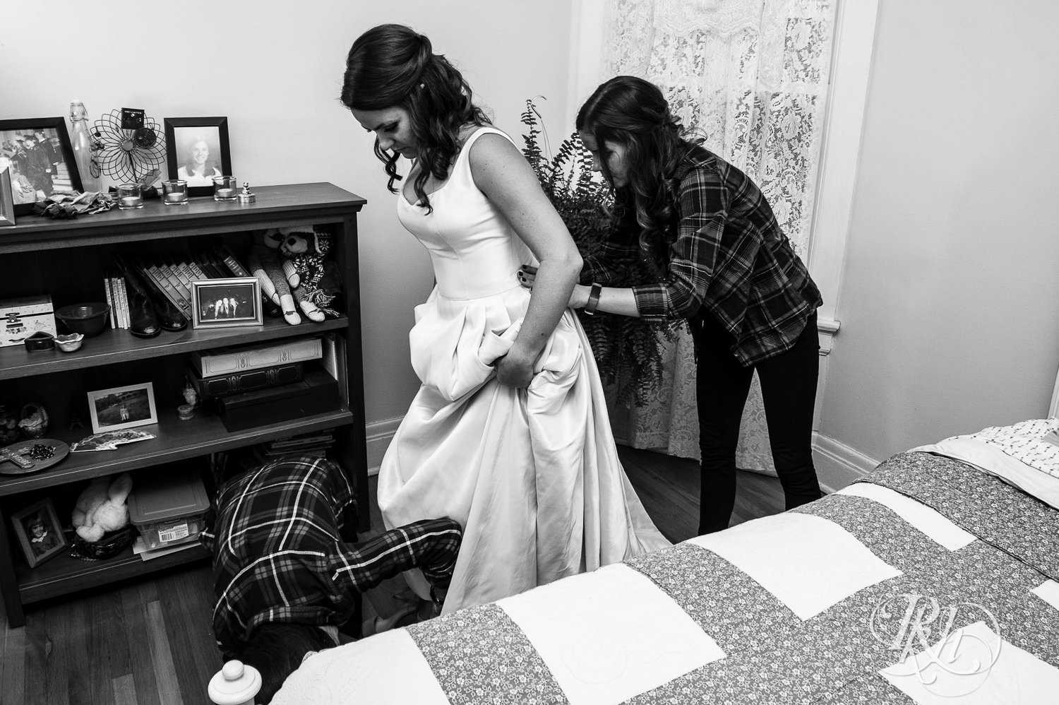 Bridesmaids help bride with her dress on her wedding day in her childhood home in Saint Paul, Minnesota.