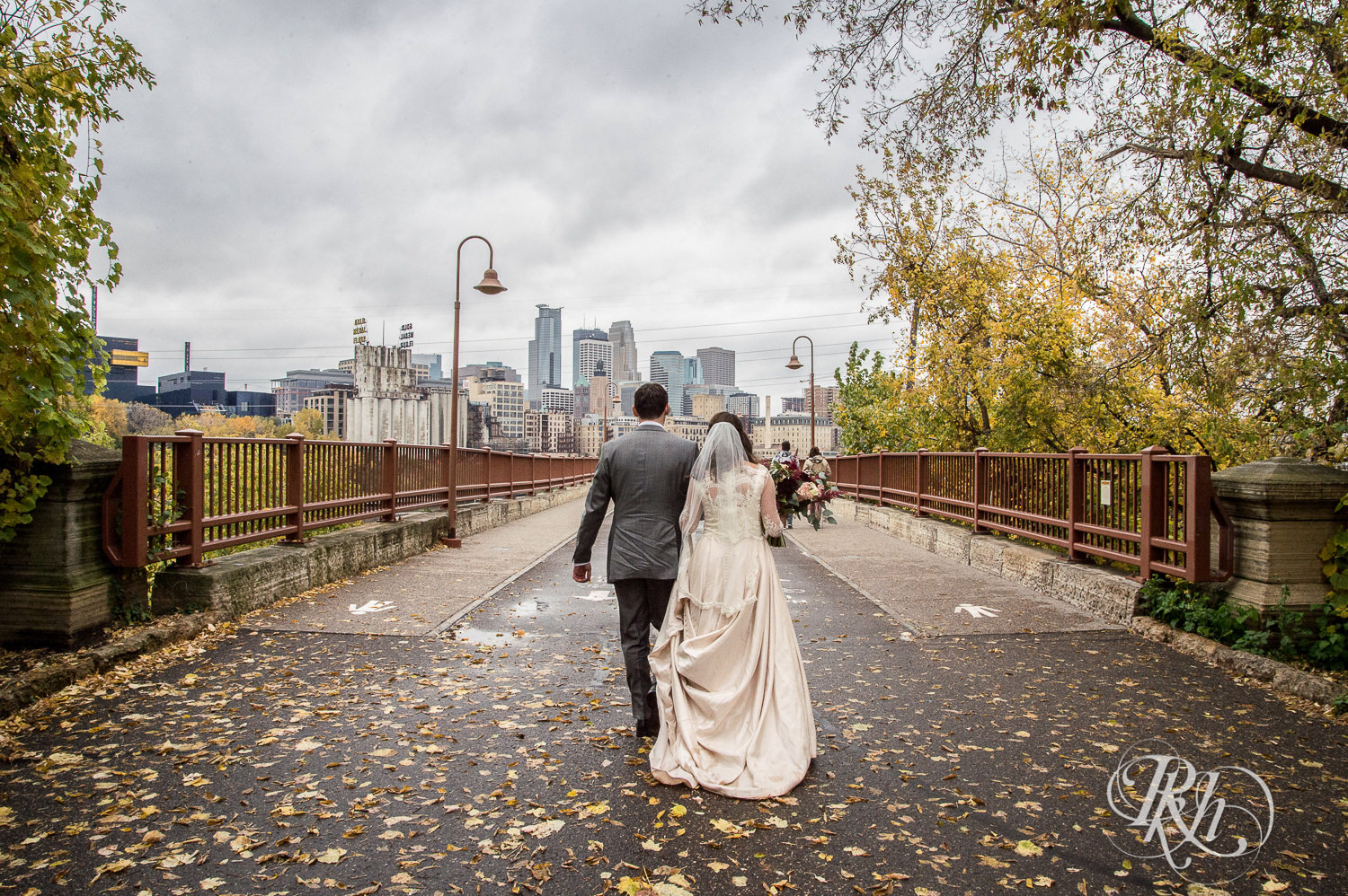 Bride and groom walk down the Stone Arch Bridge on their rainy wedding day in Minneapolis, Minnesota.
