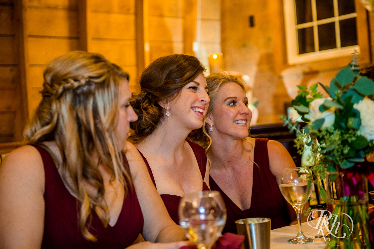 Bridesmaids smile at head table at Green Acres Event Center barn wedding in Eden Prairie, Minnesota.