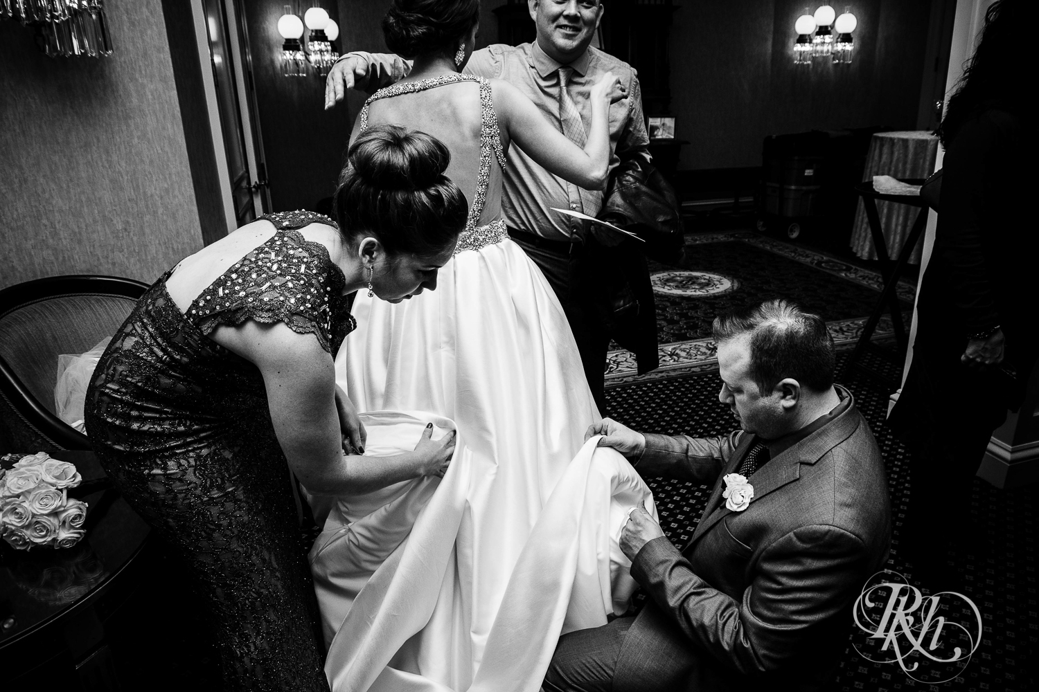 People help bride with dress at The Saint Paul Hotel in Saint Paul, Minnesota.