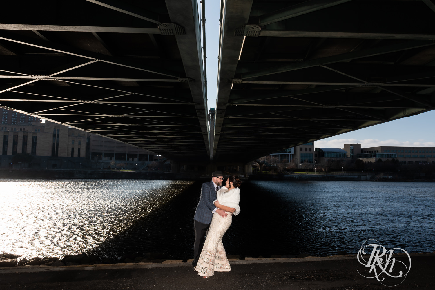 Bride and groom smile under bridge in Minneapolis, Minnesota.
