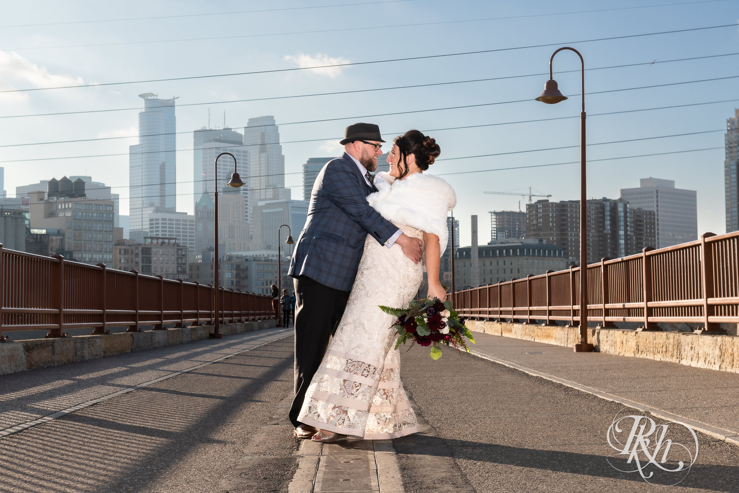 Bride and groom smile on Stone Arch Bridge in Minneapolis, Minnesota.