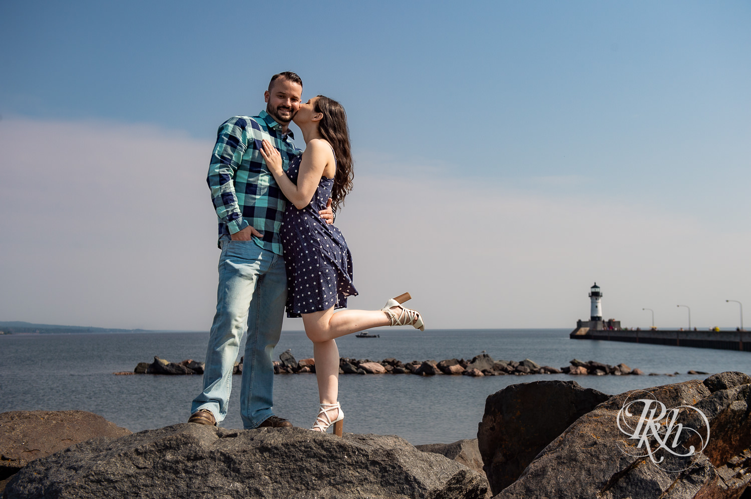Man and woman kiss in front of Lake Superior in Canal Park in Duluth, Minnesota with bird flying over them.