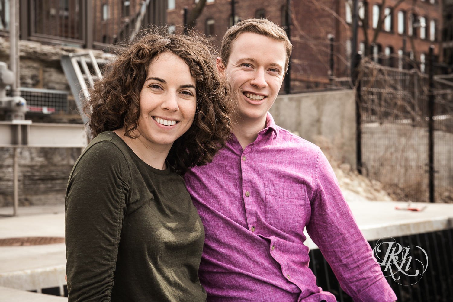 Man and woman smile during winter engagement photography in Minneapolis, Minnesota during St. Anthony Main engagement photos.