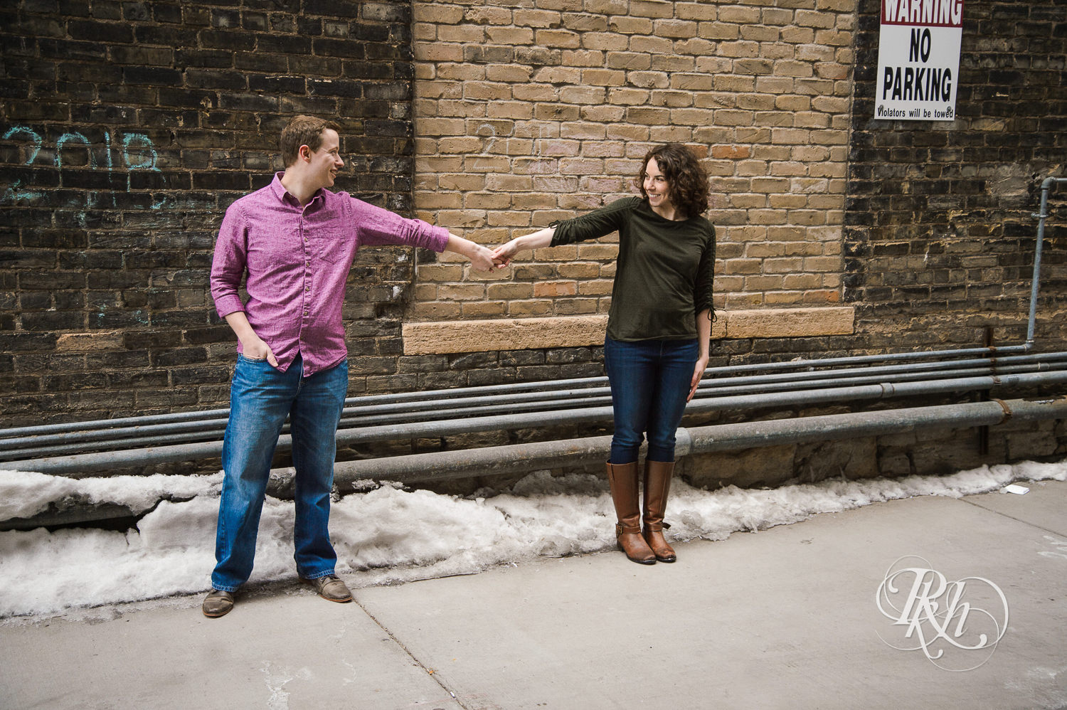 Man and woman smile in front of brick while in Minneapolis, Minnesota.
