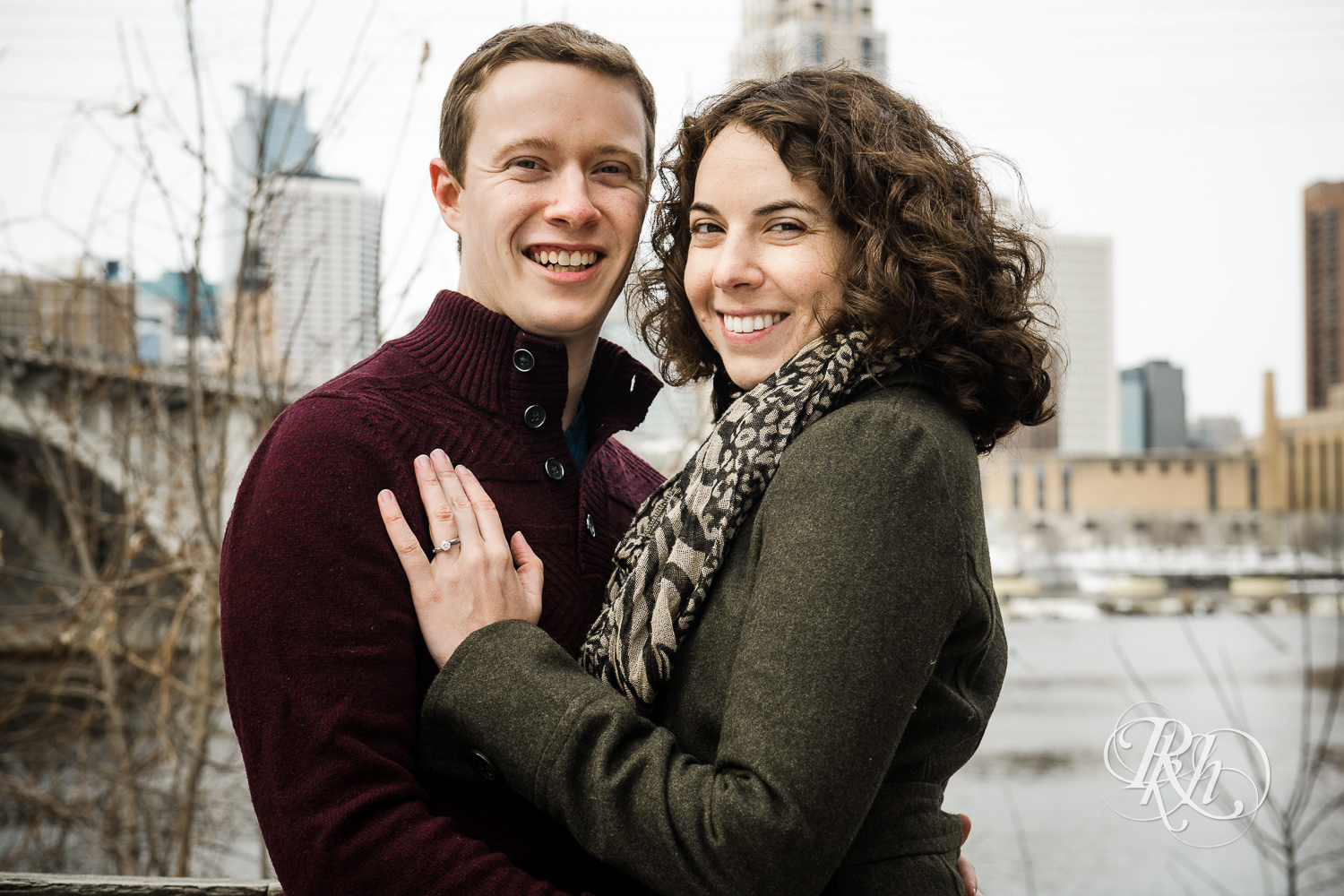 Man and woman smile during winter St. Anthony Main engagement photos in Minneapolis, Minnesota.