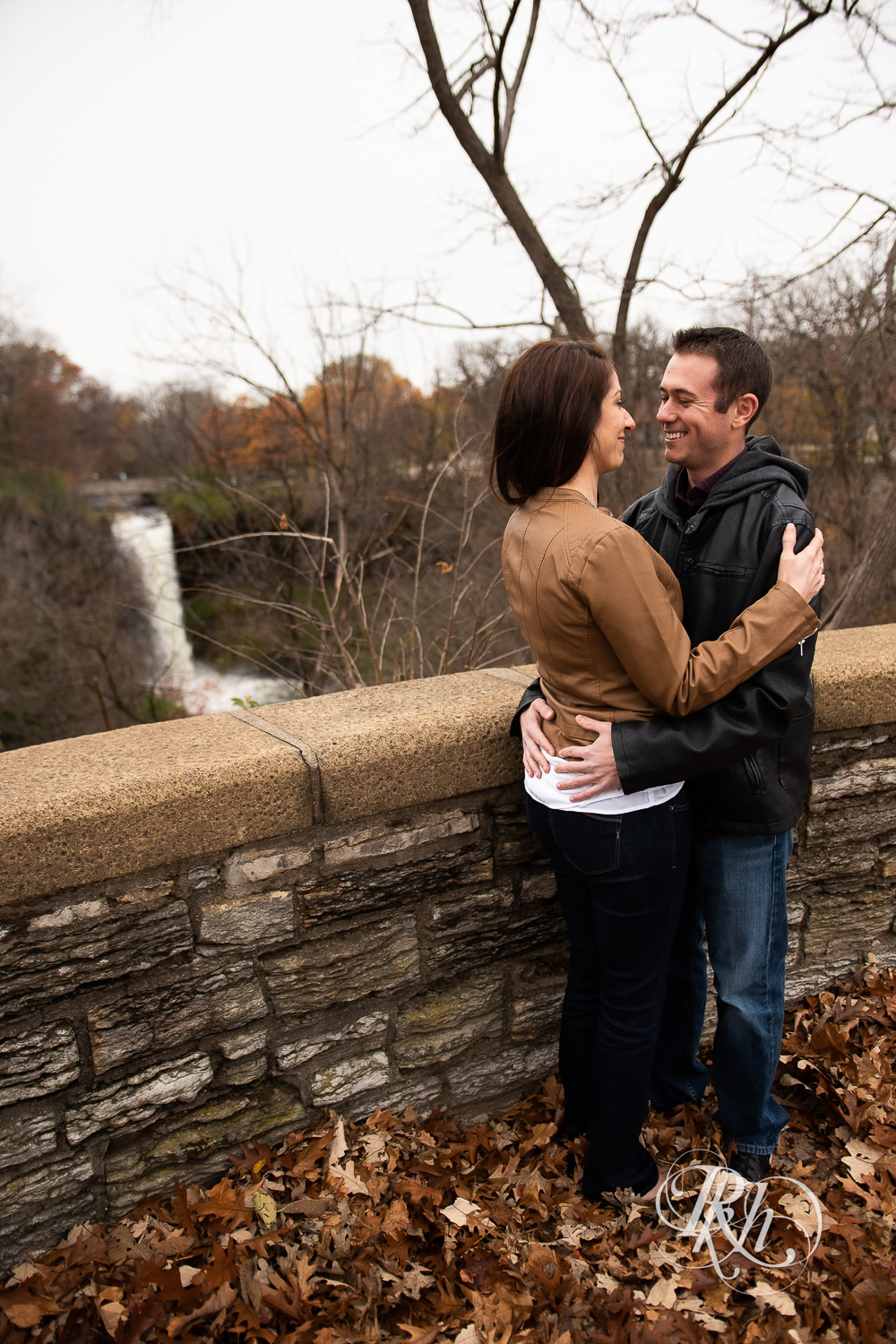 Man and woman smile during Minnehaha Falls engagement photos in Minneapolis, Minnesota.