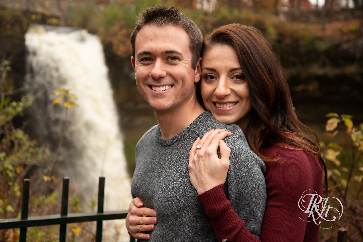 Man and woman smile in front of Minnehaha Falls in Minneapolis, Minnesota.