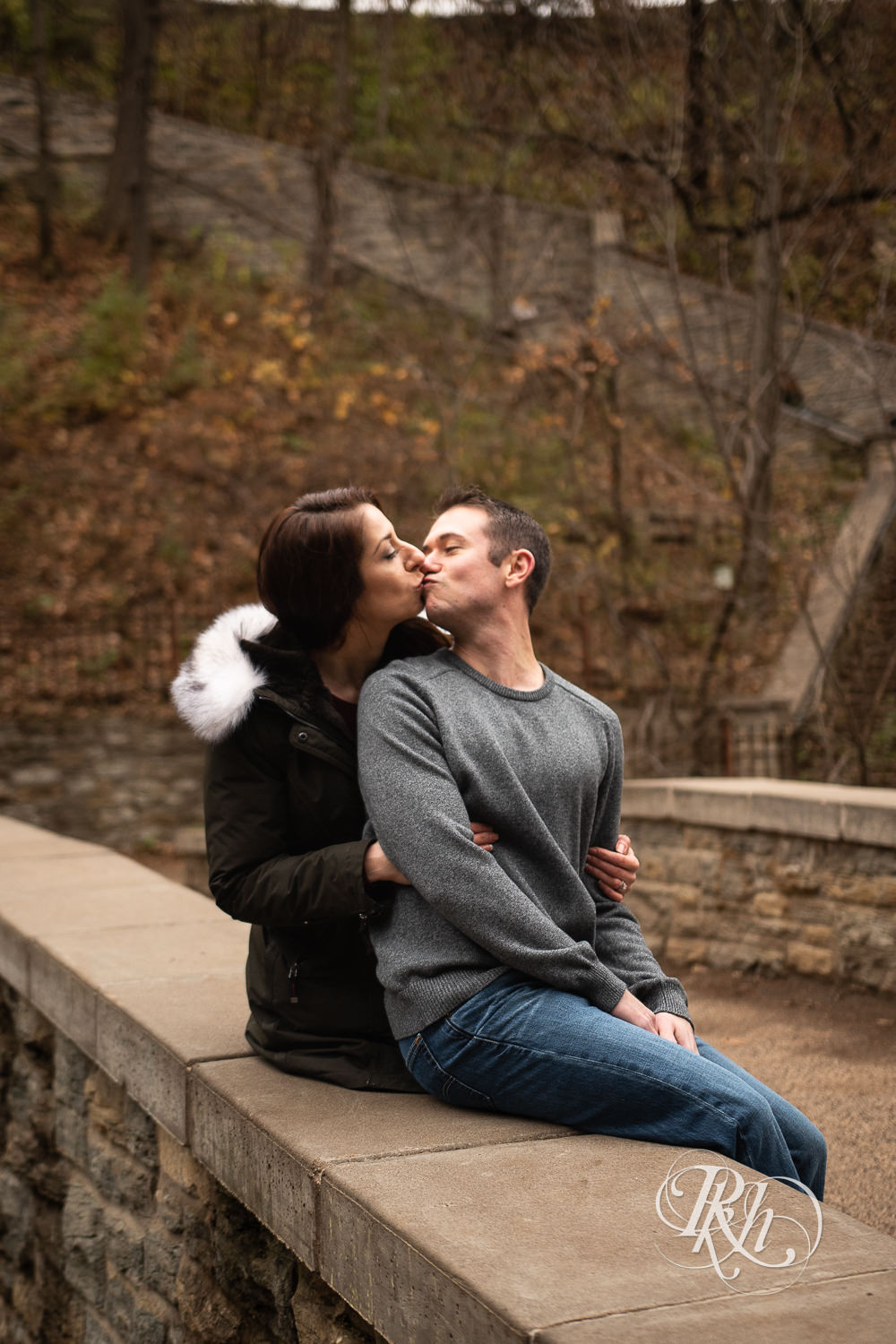 Man and woman in coat kiss in Minnehaha Falls in Minneapolis, Minnesota.
