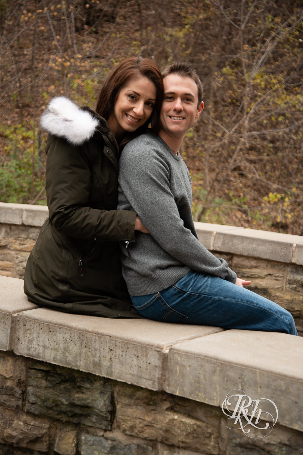 Man and woman in coat hug in Minnehaha Falls in Minneapolis, Minnesota.