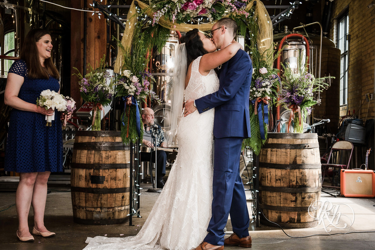 Asian bride with glasses and groom kiss during wedding ceremony at 612 Brew in Minneapolis, Minnesota.