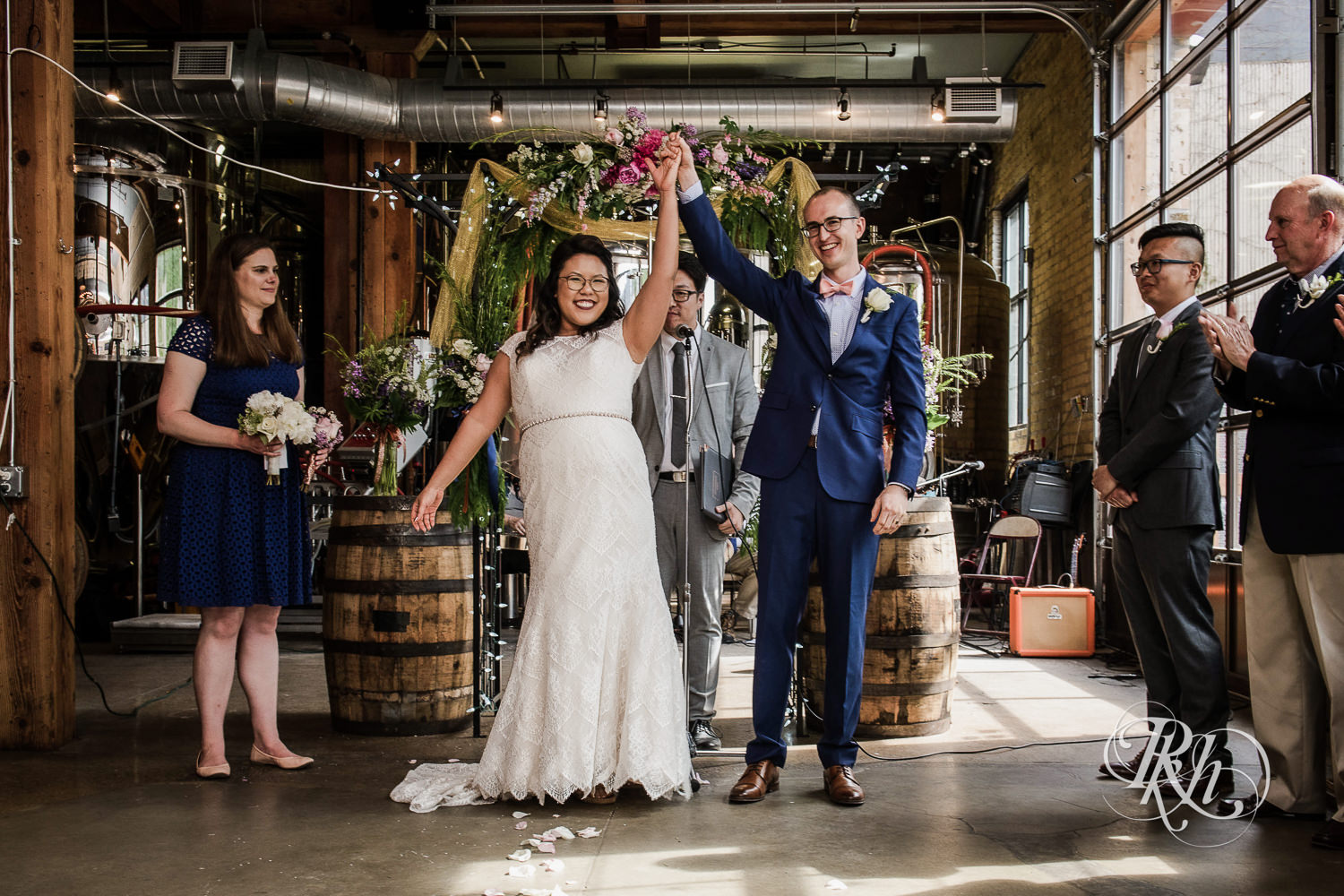 Asian bride with glasses and groom smile during wedding ceremony at 612 Brew in Minneapolis, Minnesota.