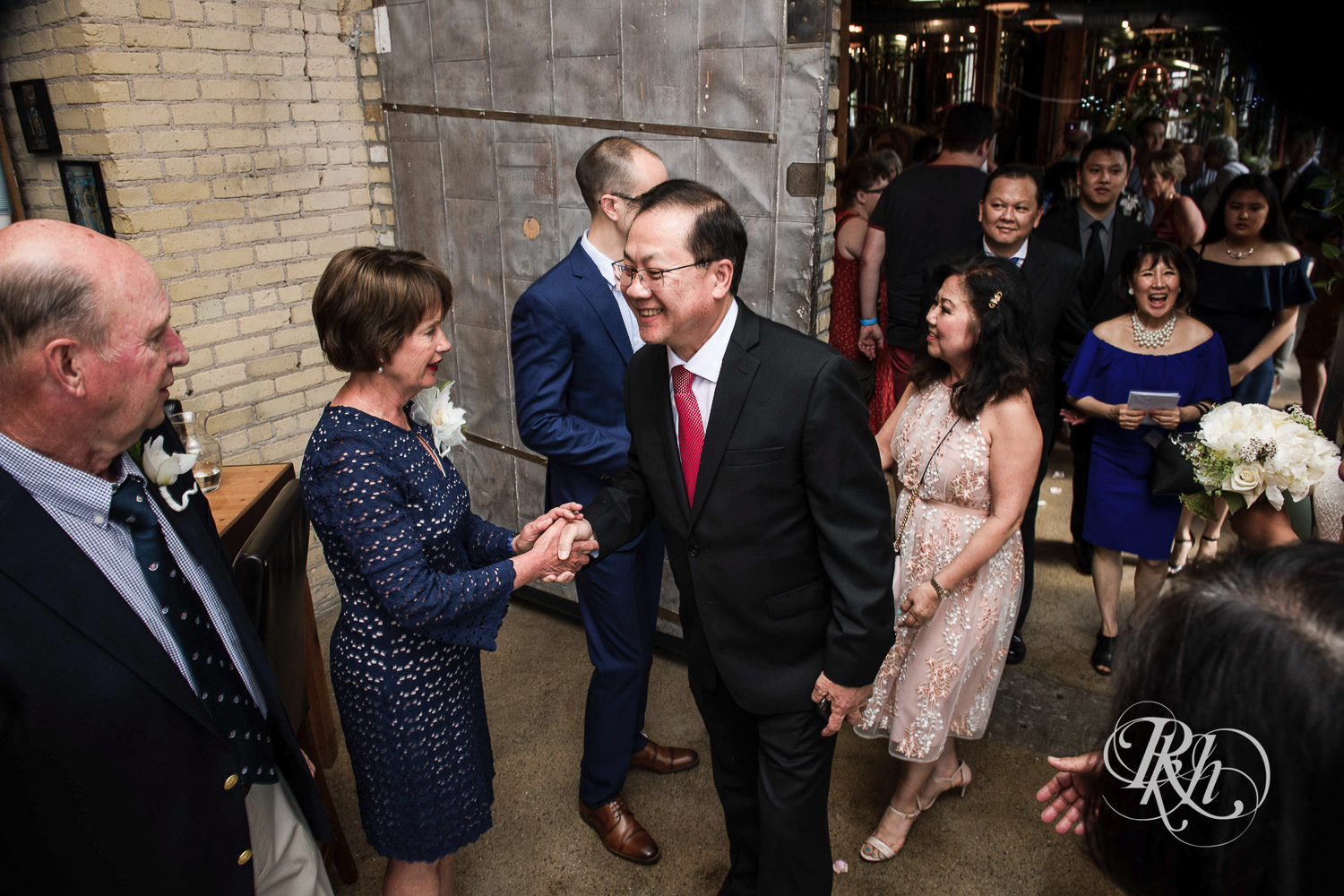 Asian bride with glasses and groom meet with guests during receiving line at 612 Brew in Minneapolis, Minnesota.