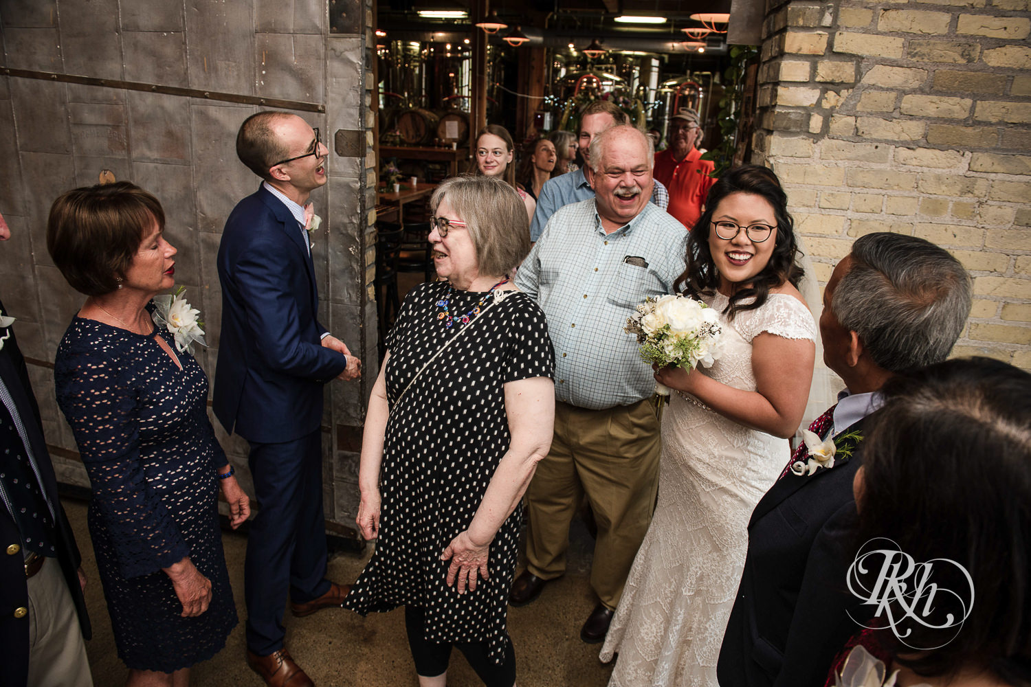 Asian bride with glasses and groom meet with guests during receiving line at 612 Brew in Minneapolis, Minnesota.