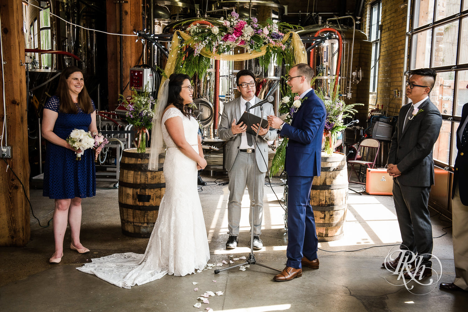 Asian bride with glasses and groom read vows during wedding ceremony at 612 Brew in Minneapolis, Minnesota.