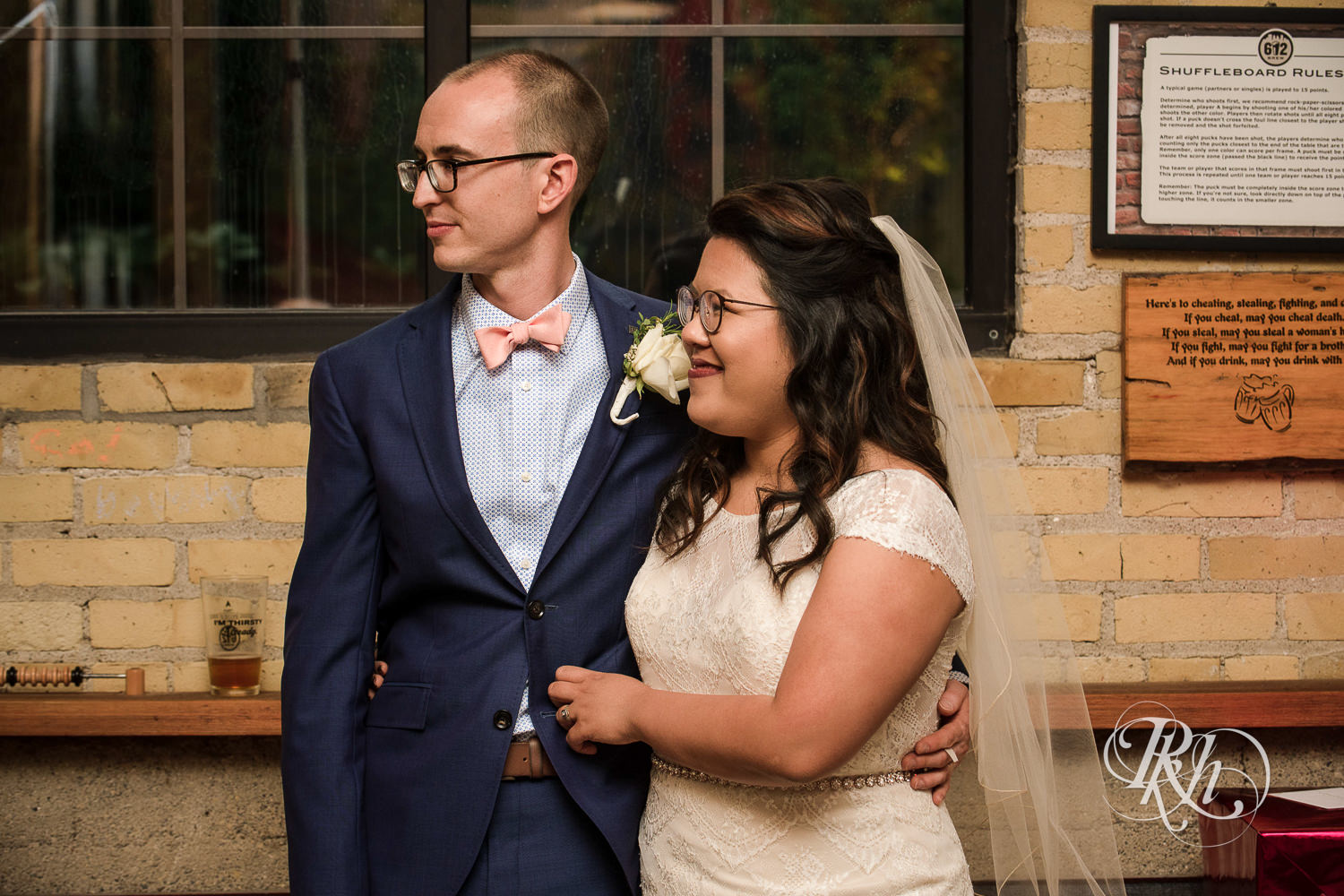 Asian bride with glasses and groom smile during wedding speeches at 612 Brew in Minneapolis, Minnesota.