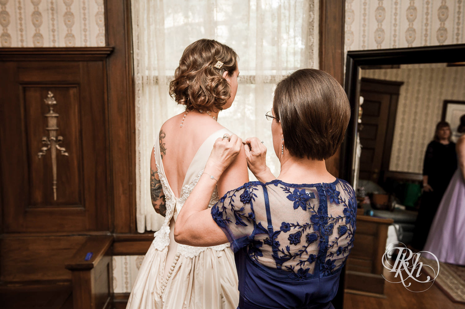 Bride getting buttoned into wedding dress at Summit Manor Reception House in Saint Paul, Minnesota.
