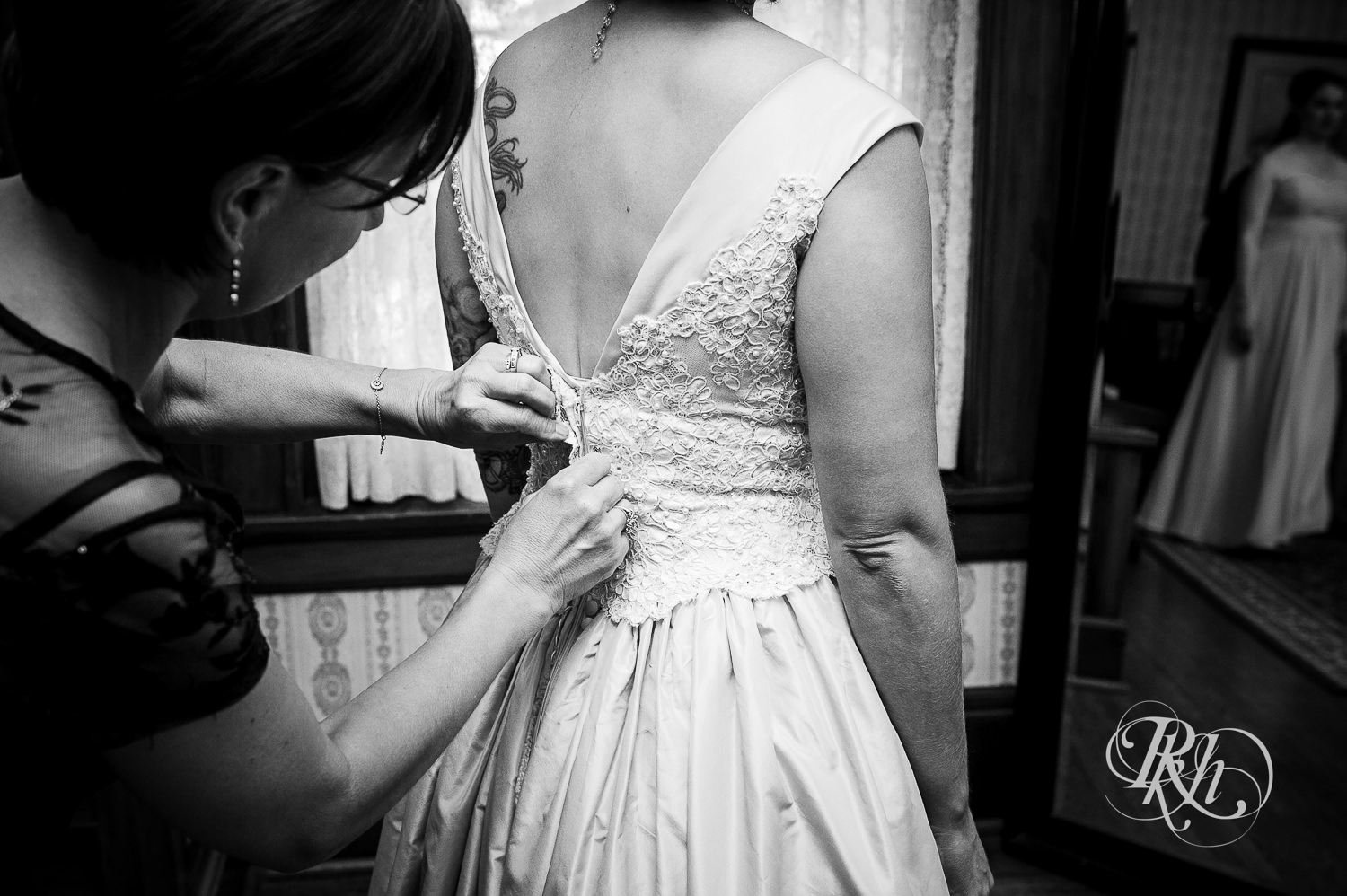 Bride getting buttoned into wedding dress at Summit Manor Reception House in Saint Paul, Minnesota.
