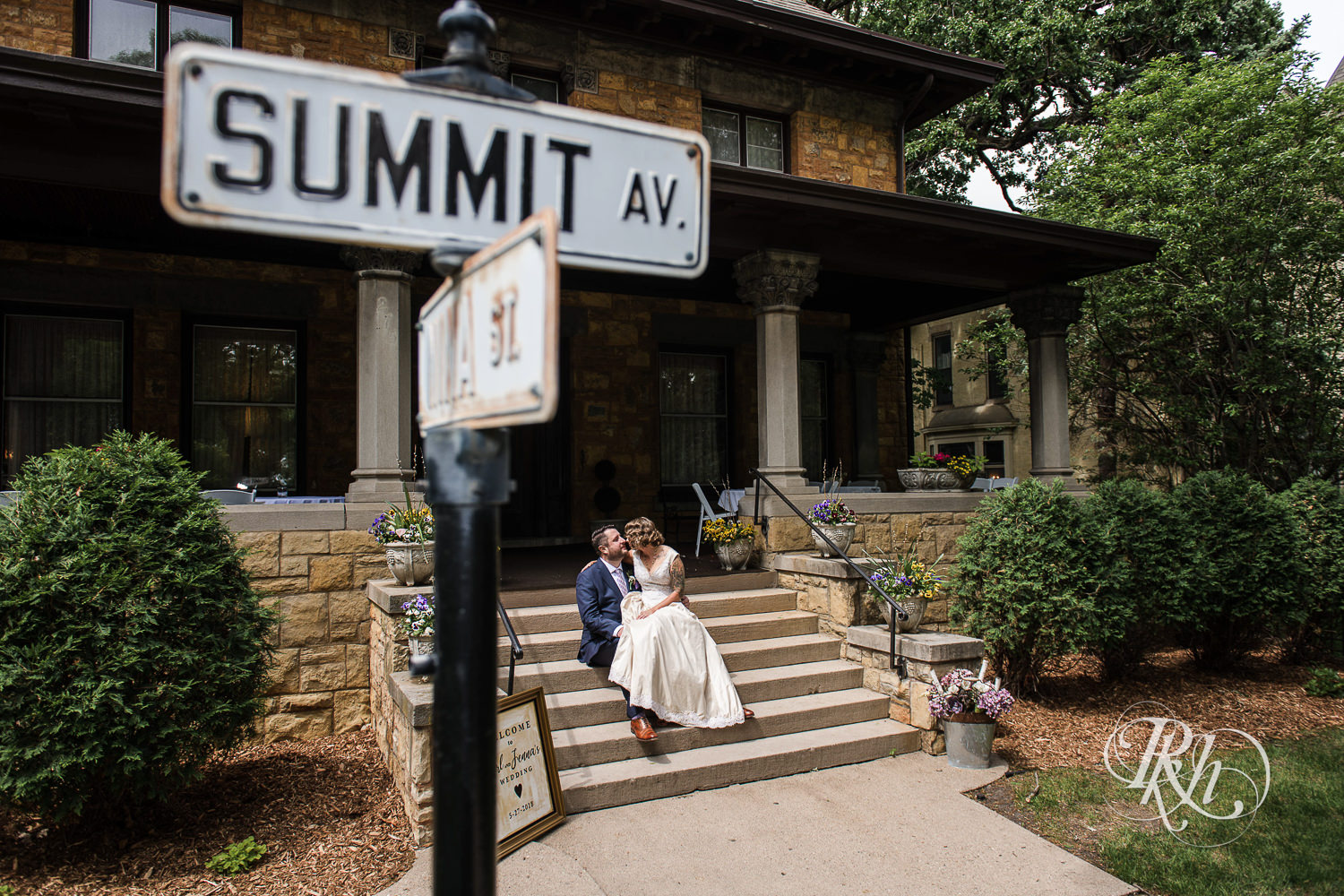 Bride and groom smile in front of Summit Manor Reception House in Saint Paul, Minnesota.