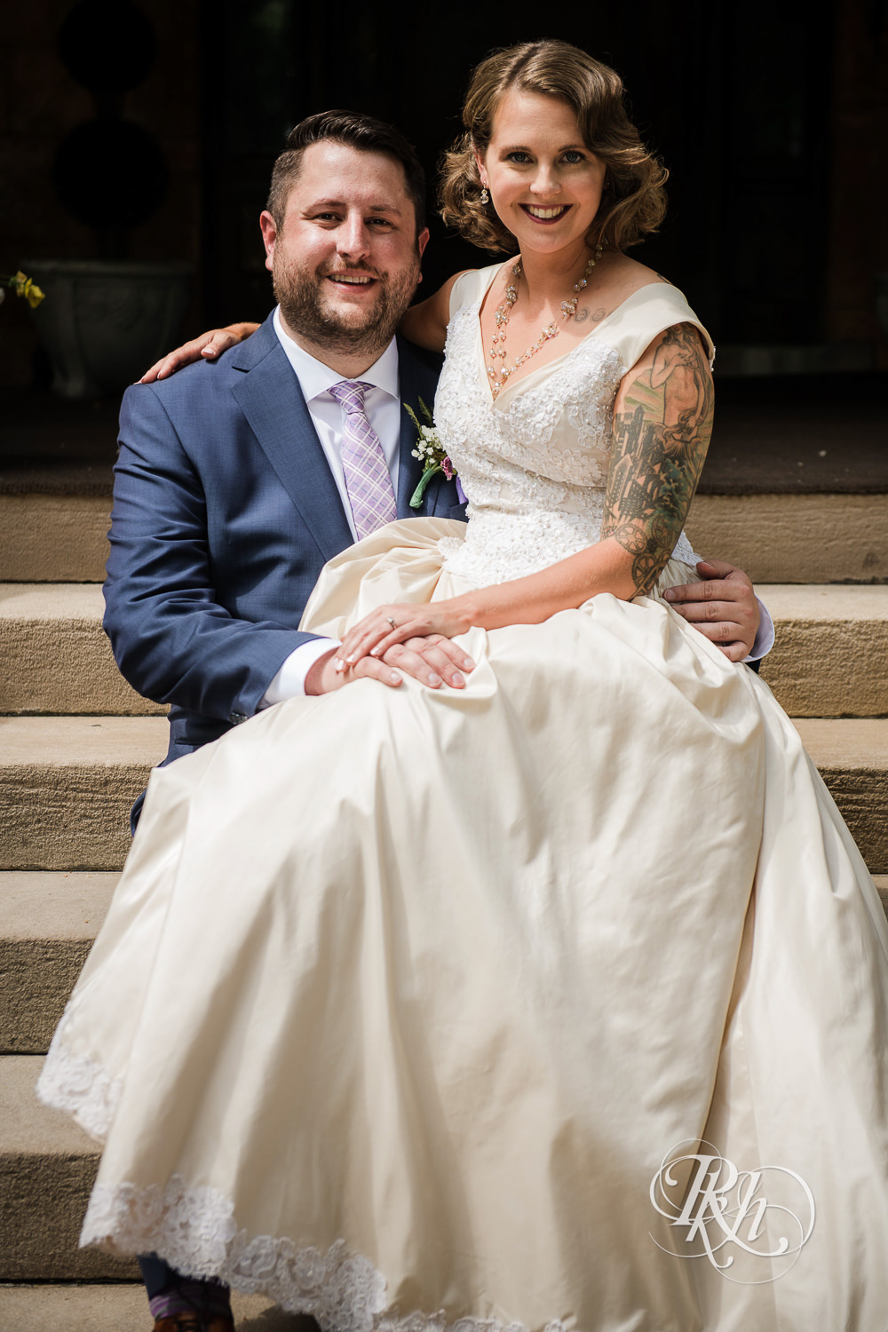 Bride and groom smile in front of Summit Manor Reception House in Saint Paul, Minnesota.