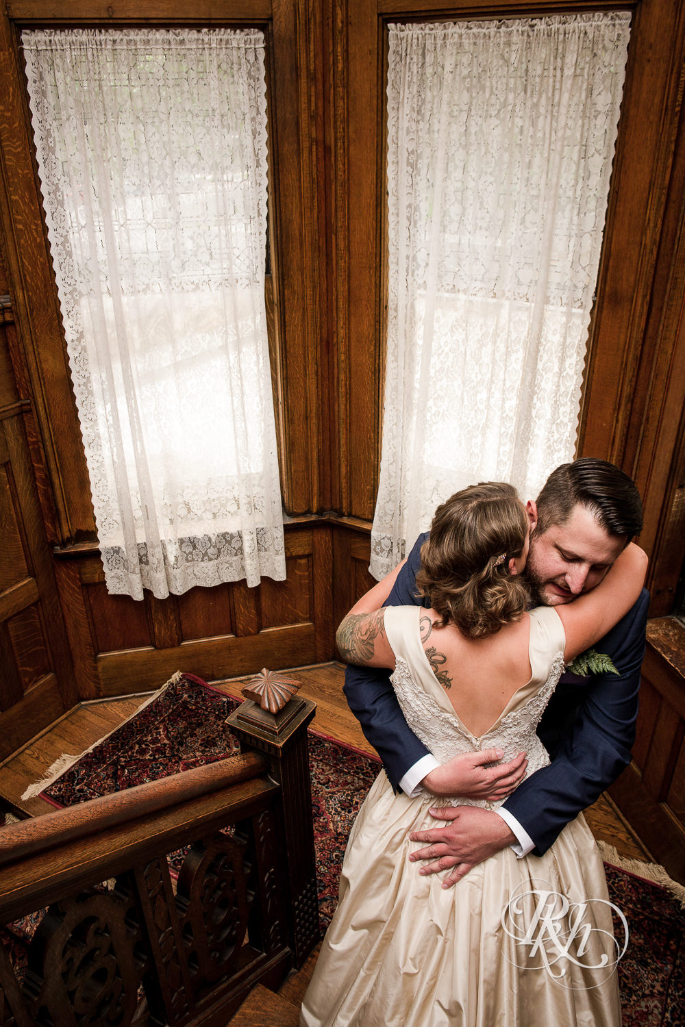 Bride and groom hug on stairs at Summit Manor Reception House in Saint Paul, Minnesota.