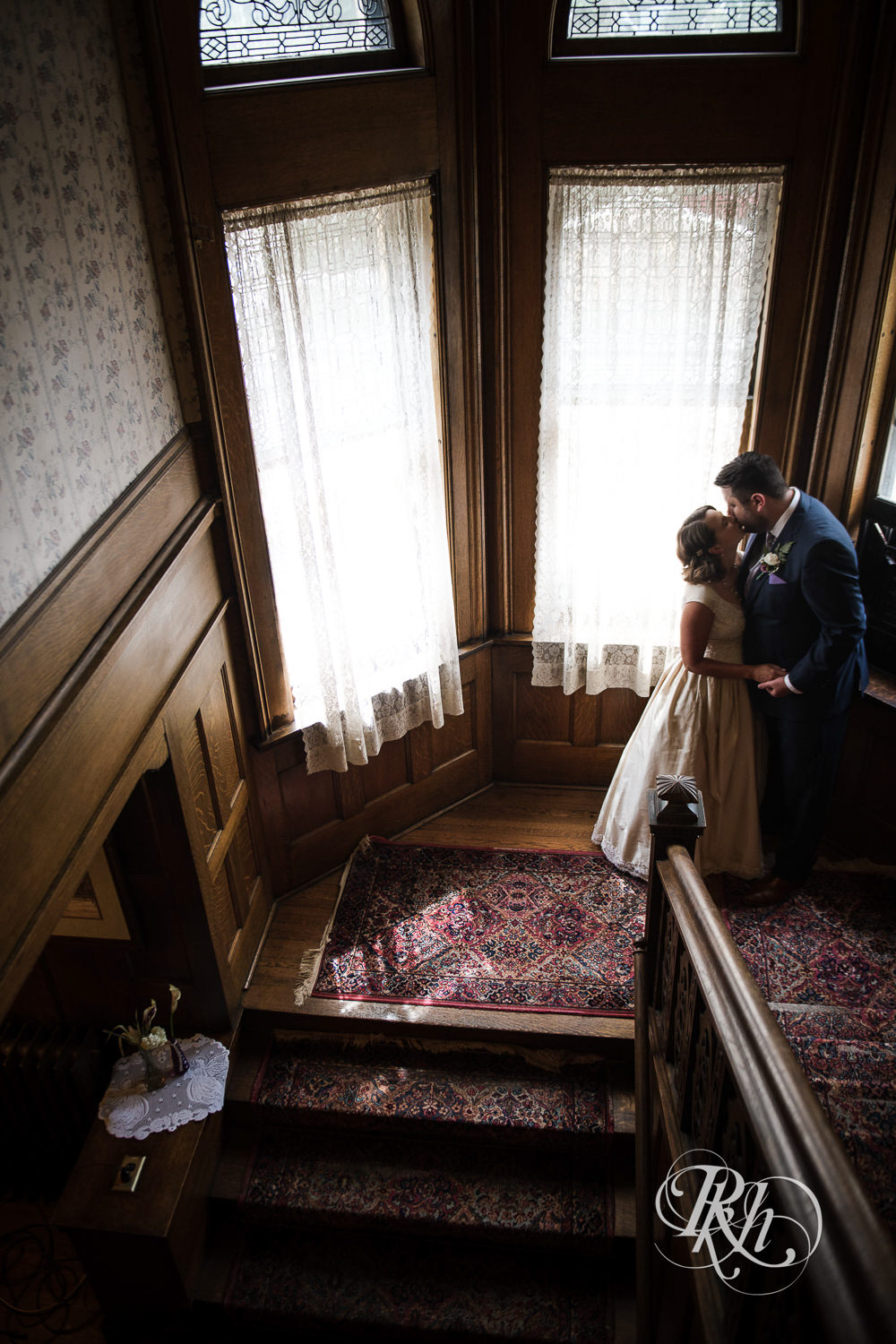 Bride and groom kiss on stairs Summit Manor Reception House in Saint Paul, Minnesota.