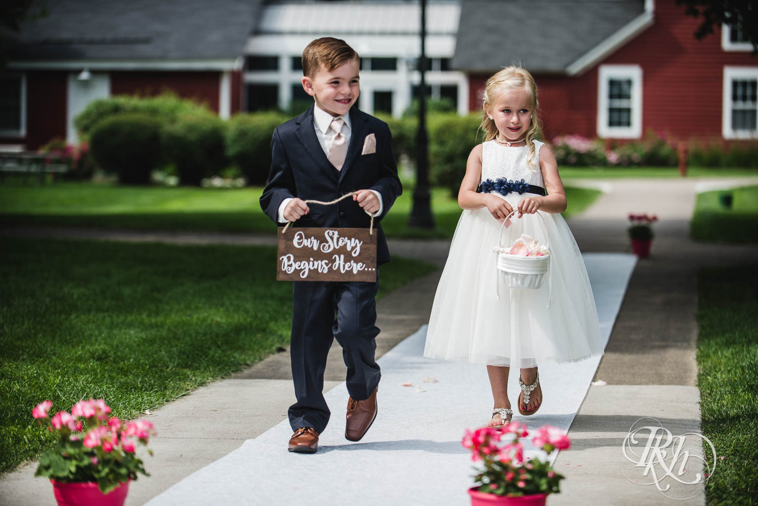 Flower girl and ring bearer walk down the aisle at Earle Brown Heritage Center in Brooklyn Center, Minnesota.