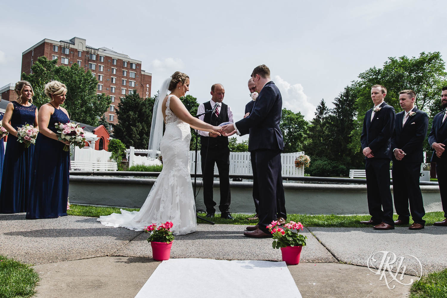 Bride and groom smile during outdoor wedding ceremony at Earle Brown Heritage Center in Brooklyn Center, Minnesota.