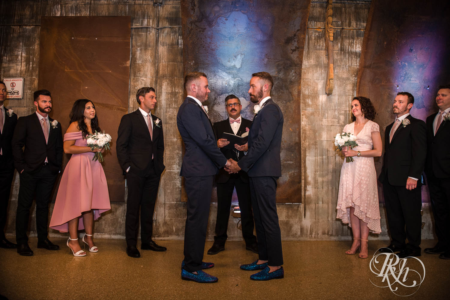 Grooms smile during LGBTQ wedding ceremony at Warehouse Winery wedding in Saint Louis Park, Minnesota.