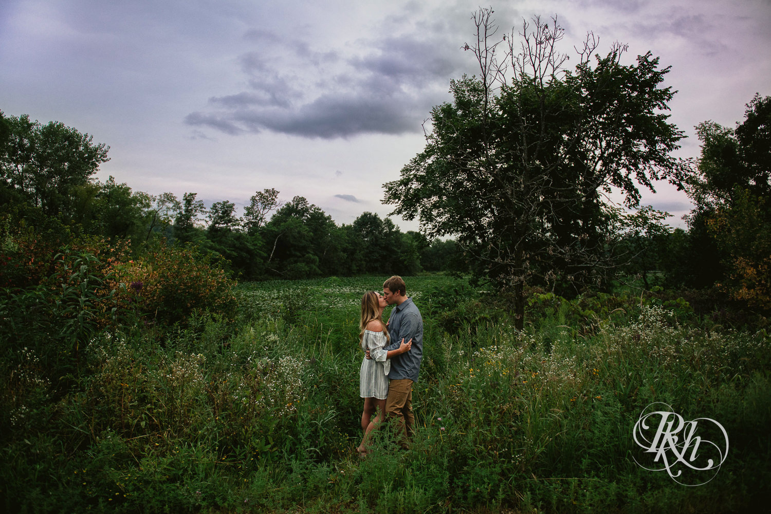 Man and woman kiss in field at sunrise in Lebanon Hills Regional Park in Eagan, Minnesota.