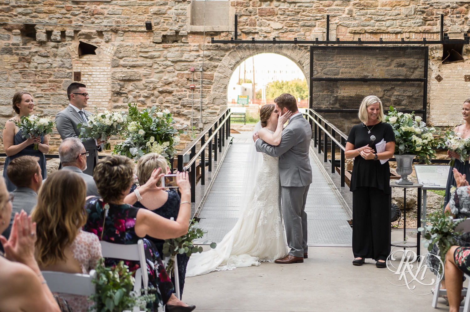 Bride and groom kiss during outdoor wedding ceremony in Mill City Museum in Minneapolis, Minnesota.