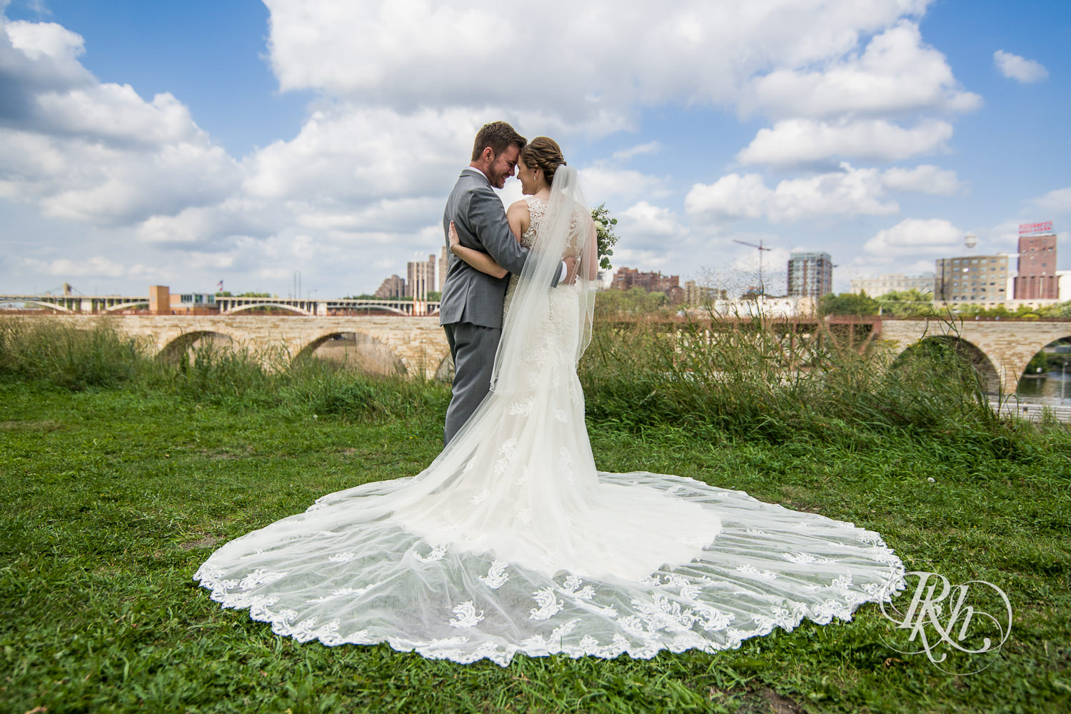 Bride and groom smile in front of Minneapolis skyline at Mill City Museum in Minneapolis, Minnesota.