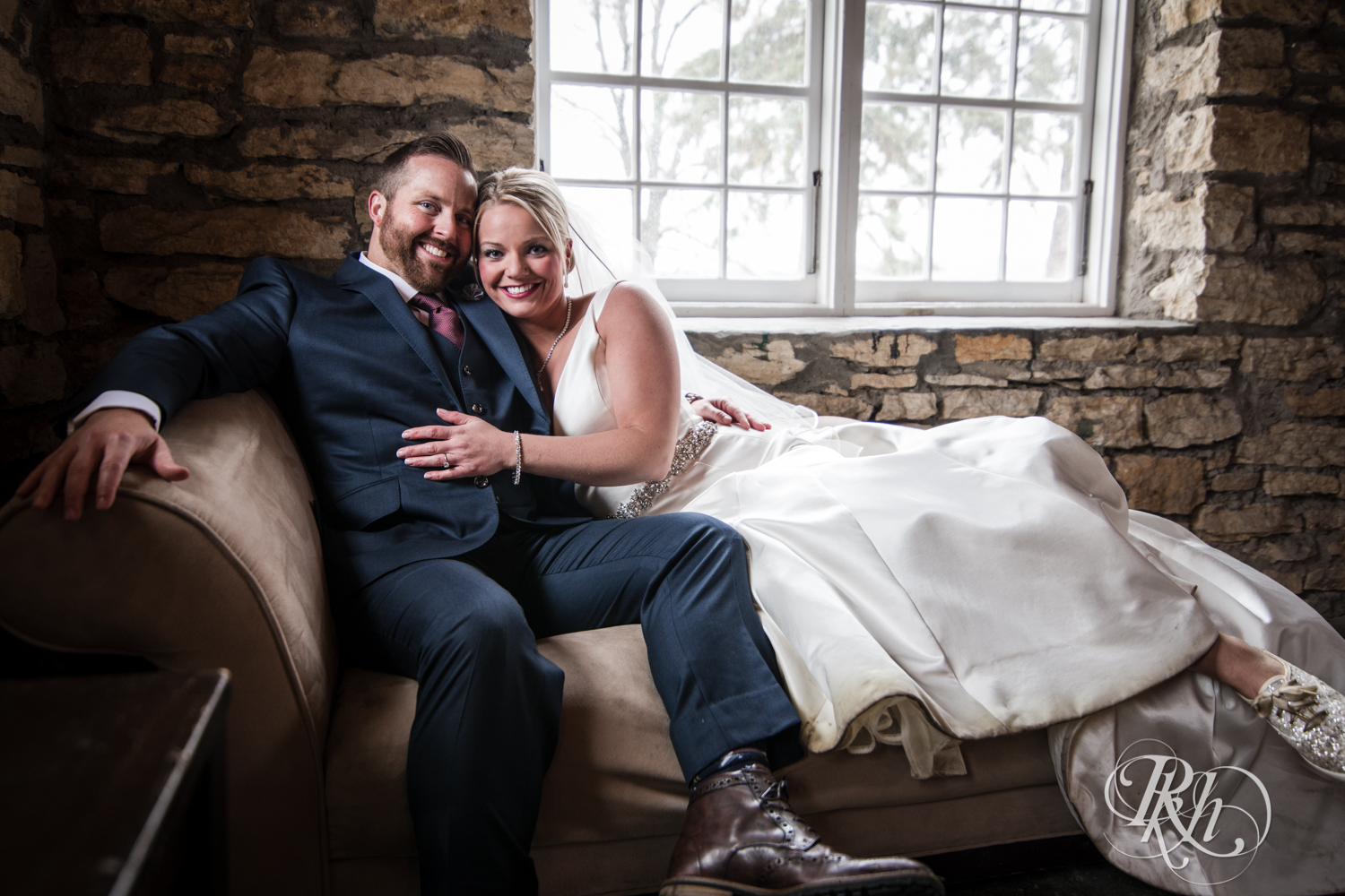 Bride and groom snuggle on couch at Mayowood Stone Barn in Rochester, Minnesota.