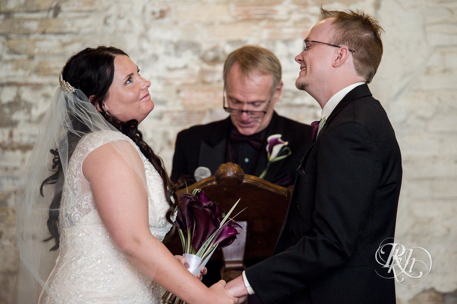 Bride and groom smile during indoor wedding ceremony at Kellerman's Event Center in White Bear Lake, Minnesota.