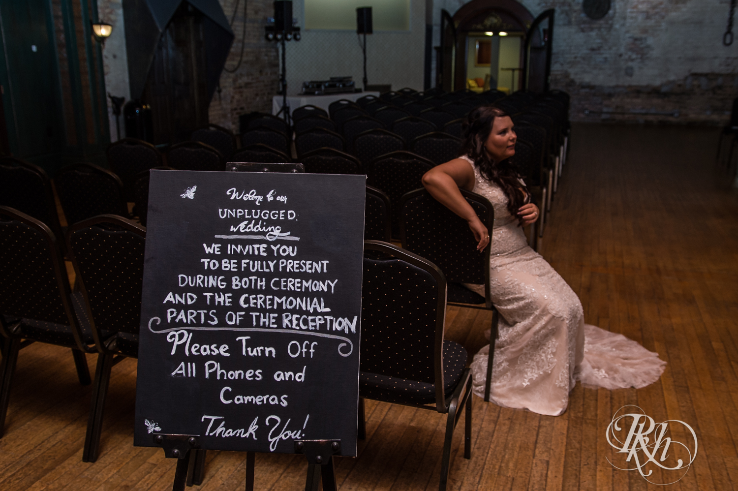 Bride sitting next to unplugged ceremony sign at Kellerman's Event Center in White Bear Lake, Minnesota.