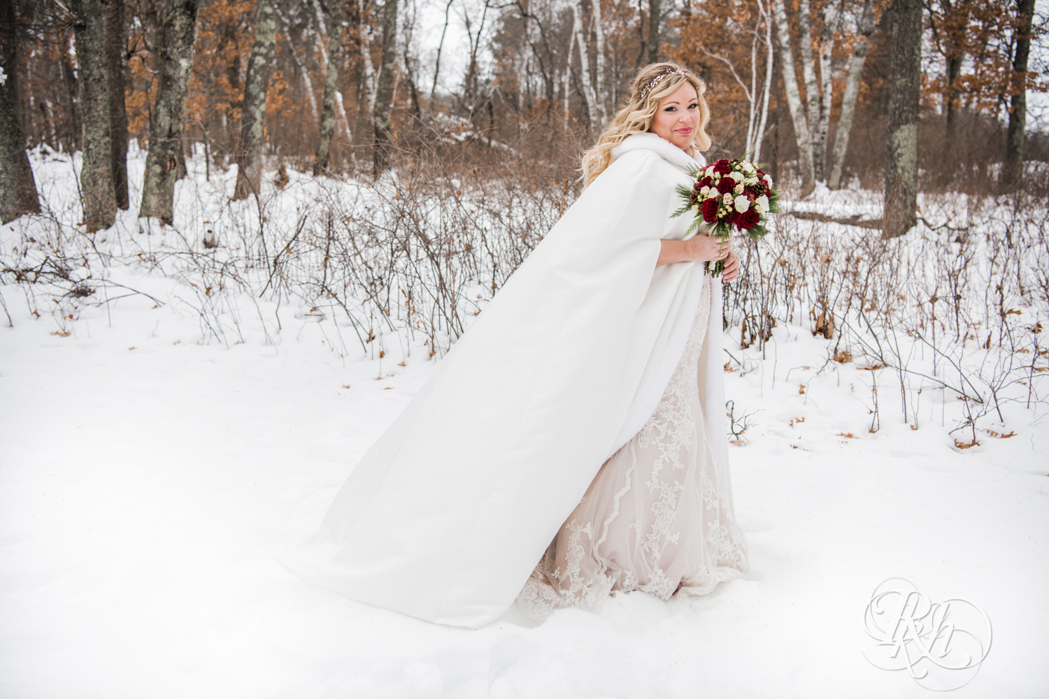 Bride holds roses in snow during winter wedding at Whitefish Lodge in Crosslake, Minnesota.