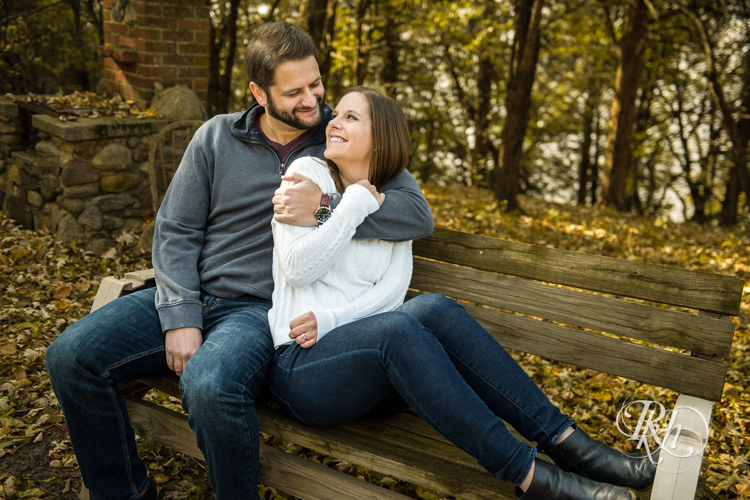 Man and woman smile in on a bench during engagement photography session at home in Annandale, Minnesota.